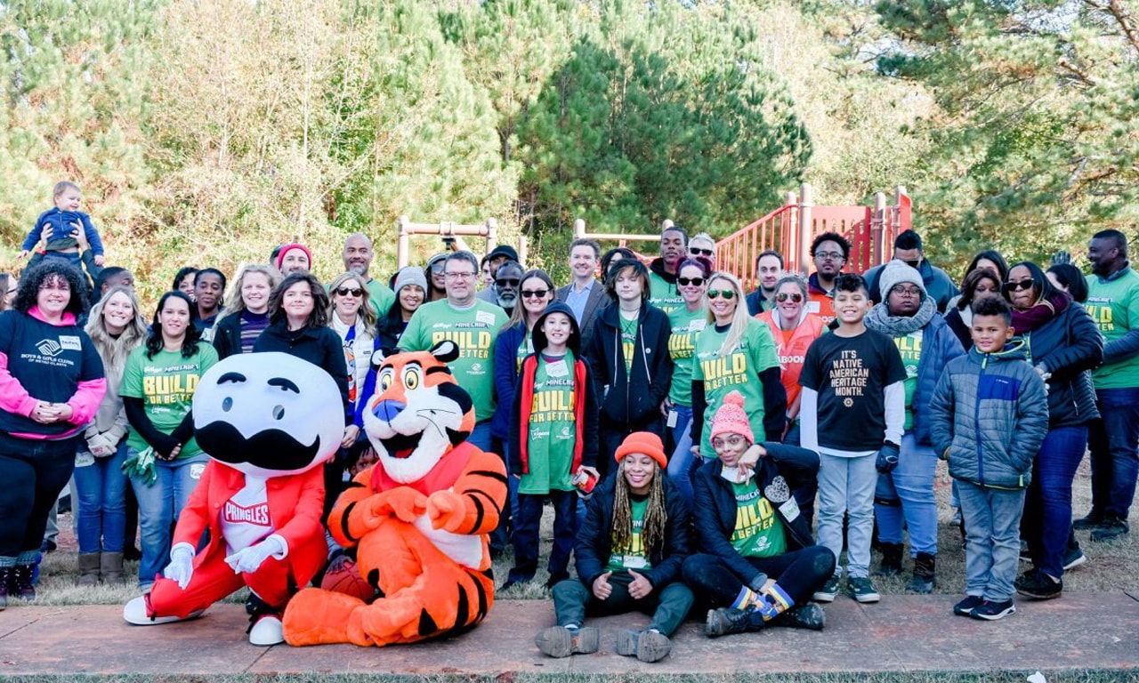 Group photo of volunteers with mascots Tony the Tiger and Pringles, gathered at a community playground event.