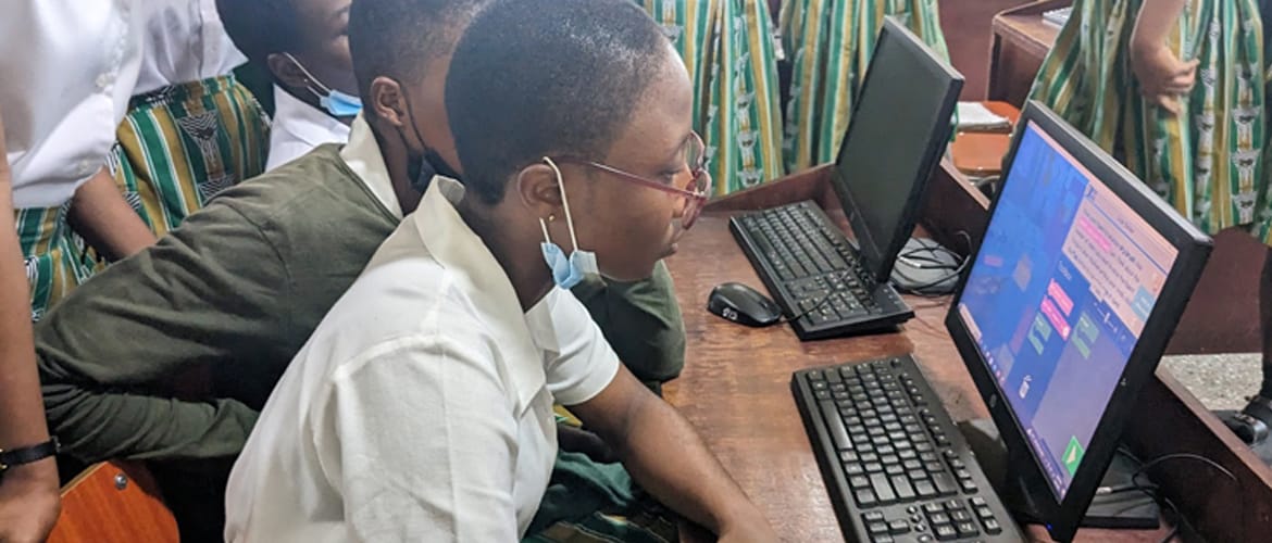 Several African students wearing school uniforms use Minecraft Education on desktop computers